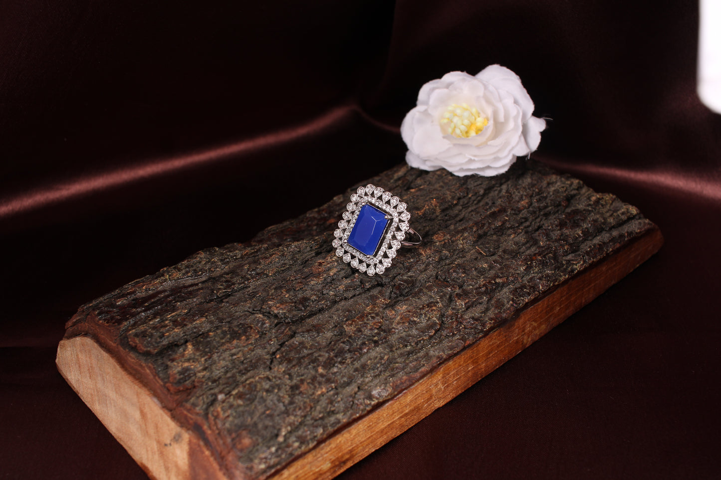 CKLAKART's Silver-Toned Statement Ring with Blue Sapphire Center and White Stone Embellishments