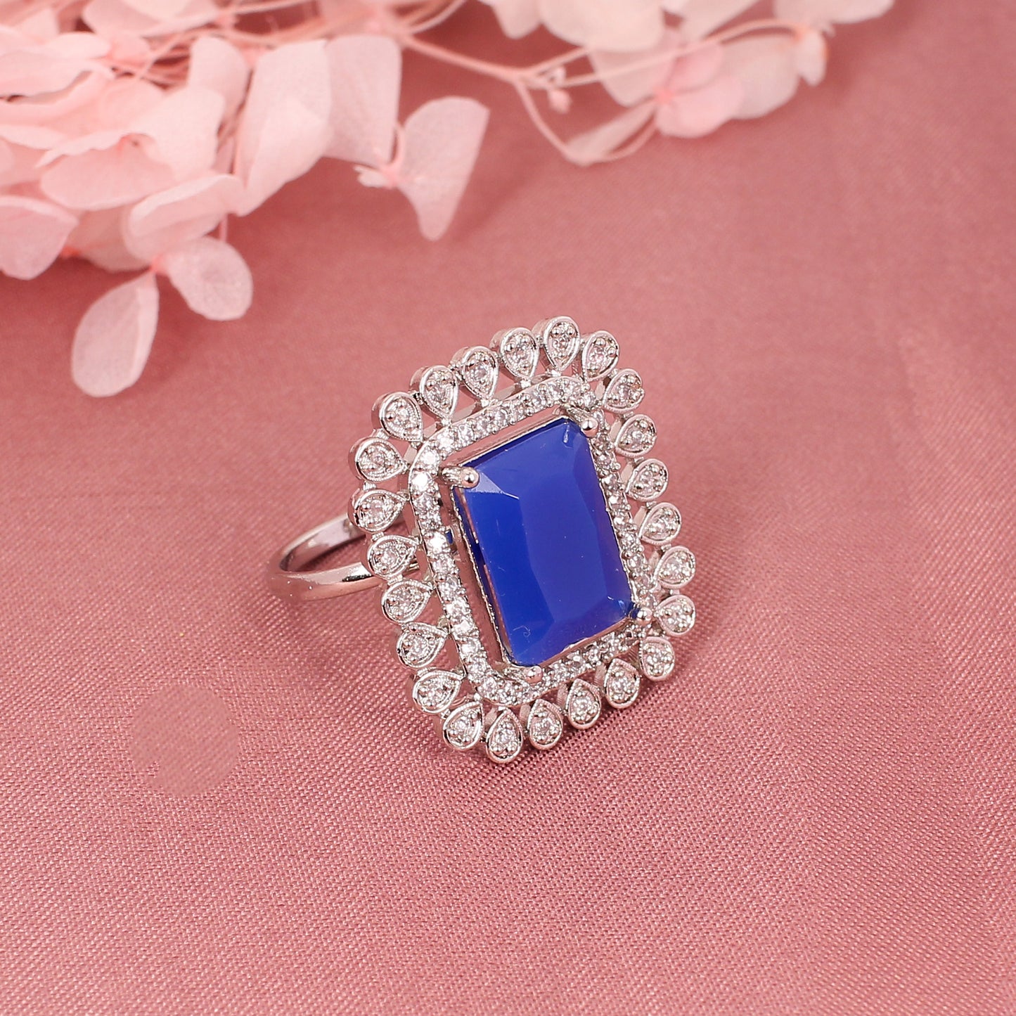 CKLAKART's Silver-Toned Statement Ring with Blue Sapphire Center and White Stone Embellishments